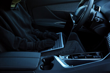 Thief hacking car system with laptop inside vehicle, closeup
