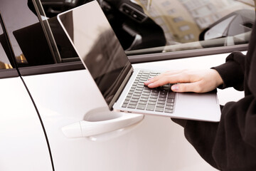 Thief hacking car system with laptop near vehicle, closeup