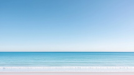 Serene beach scene with clear blue sky and calm ocean waves.