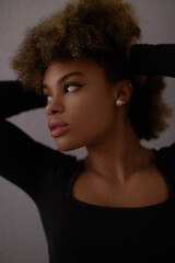 Fototapeta premium a close-up portrait of a person with curly hair, wearing a black top and an earring