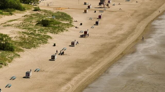 Telephoto drone shot of people on the Parnu beach, sunny, summer day in Estonia