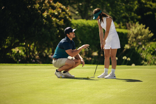 Golf instructor coaching female player discussing shot on the green