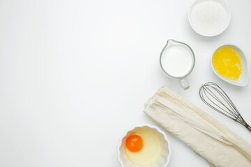 Near baking dish with ingredients, phyllo dough, egg, butter, nuts, and milk on a white background for baking Crinkle Cake