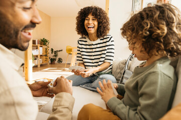 Family enjoying a playful and cheerful time together playing a card game in a bright living room.