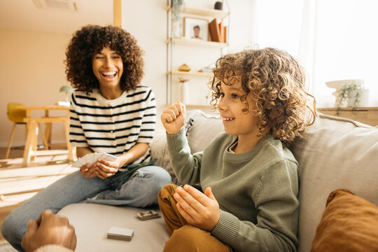 Family members playing a casual card game together in a bright cozy living room, showcasing happiness, togetherness, and a warm family bond.