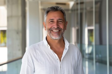 Fototapeta premium Portrait of a joyful man in his 50s wearing a simple cotton shirt isolated in sophisticated corporate office background