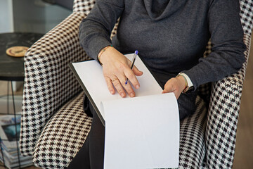 A Woman sitting in a chair writing on a clipboard