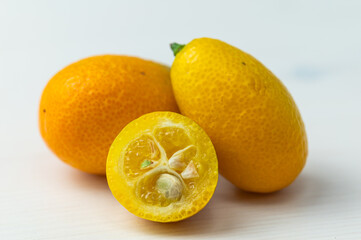 Ripe Chinese mandarins, or Kingen, on white wooden surface.