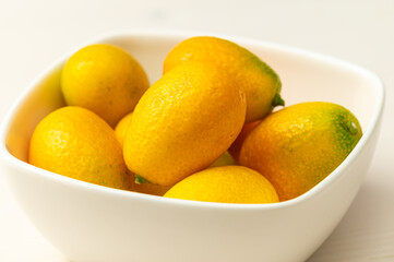 Ripe Chinese mandarins, or Kingen, on white wooden surface.