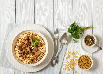 pasta rings topped with braised meat in bowl