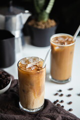 Vertical photo, Iced a coffee cup on the glass cup with roasted beans coffee and an Italian moka coffee pot on the wooden table