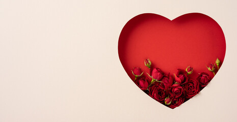 A red heart-shaped cutout filled with red roses on a white background symbolizes love and romance