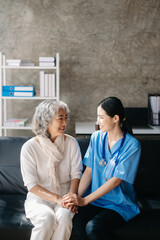 Asian caregiver doctor examine older patient woman therapist nurse at nursing home taking care of senior elderly woman sit on sofa