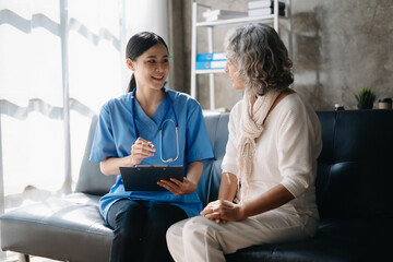 Asian caregiver doctor examine older patient woman therapist nurse at nursing home taking care of senior elderly woman sit on sofa