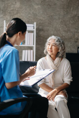 Asian caregiver doctor examine older patient woman therapist nurse at nursing home taking care of senior elderly woman sit on sofa