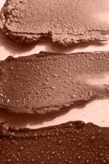 Demonstrating color of the year 2025. Mocha mousse color swatch. Cosmetic smears on beige background. Lipstick or lip gloss swatch macro wallpaper. Beauty swash texture.