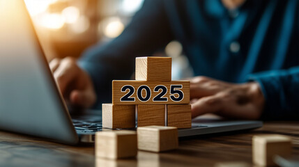 2025 New Year Celebration - Wooden Number Blocks, a businessman working with a laptop and building block stacks up to the number "2025" on a digital screen background for the new year 