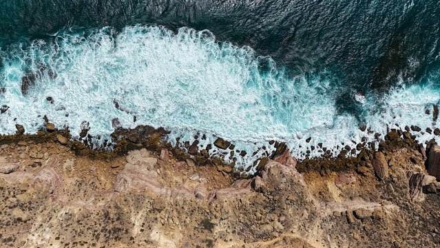 Aerial view of rocky coastline with crashing waves.