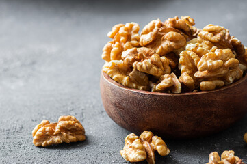 Ripe and fresh walnut kernels in bowl or burlap sack without shell on rustic table, healthy nut food for brain