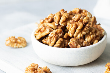 Ripe and fresh walnut kernels in bowl or burlap sack without shell on rustic table, healthy nut food for brain