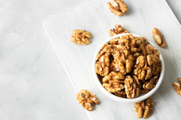 Ripe and fresh walnut kernels in bowl or burlap sack without shell on rustic table, healthy nut food for brain