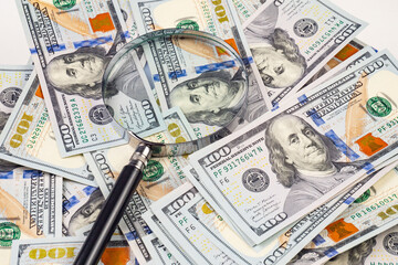 Close up of dollar banknotes and magnifying glass on chart background