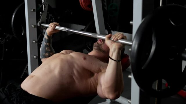 A detailed view of a young, fit man performing a bench press exercise using a Smith machine, his chest muscles clearly visible.