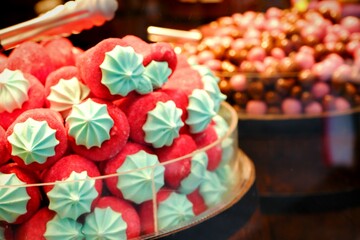 A close-up of colorful candies and macarons displayed in a dessert shop window. Food industry. Dessert varieties. Junk food, fun candies.