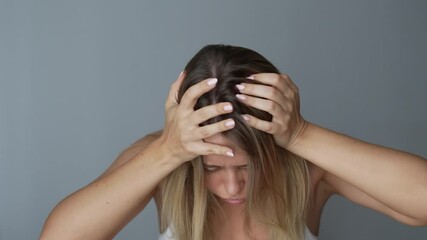 Young blonde woman feeling dizzy suffering from a severe headache holding her head with hands on a dark grey background. Dizziness, vertigo, fatigue, low blood pressure, anemia, migraine, exhaustion