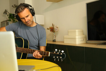 A man sitting in front of the computer practicing online music lessons