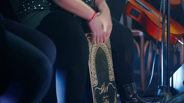 Plump woman plays cajon performing at flamenco party