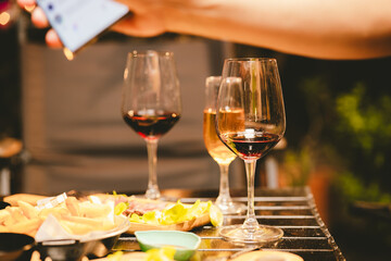 Close-up photo of people congratulating, toasting and touching wine and champagne glasses at a garden party with friends on a warm summer day.