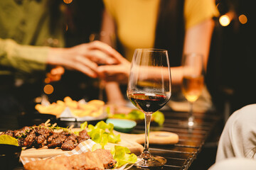 Close-up photo of people congratulating, toasting and touching wine and champagne glasses at a garden party with friends on a warm summer day.