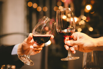 Close-up photo of people congratulating, toasting and touching wine and champagne glasses at a garden party with friends on a warm summer day.