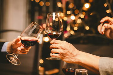 Close-up photo of people congratulating, toasting and touching wine and champagne glasses at a garden party with friends on a warm summer day.