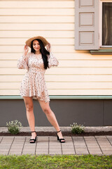 A young woman in a summer dress and hat enjoys a carefree holiday on a sunny day. A holiday feeling in a small town, by nature. 