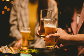 A cheerful group of young adults enjoys a lively night out, raising glasses in a celebratory toast. Laughter and smiles fill the air as friends bond over drinks in a vibrant social gathering.