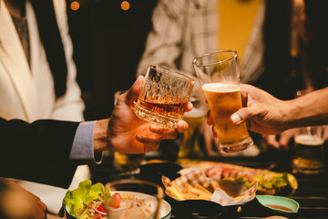 A cheerful group of young adults enjoys a lively night out, raising glasses in a celebratory toast. Laughter and smiles fill the air as friends bond over drinks in a vibrant social gathering.