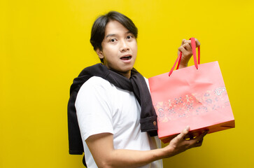 Side view of Happy Surprised Young Asian Man Holding Shopping Bags in Excitement