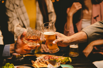 A cheerful group of young adults enjoys a lively night out, raising glasses in a celebratory toast. Laughter and smiles fill the air as friends bond over drinks in a vibrant social gathering.