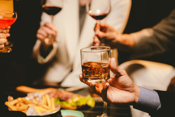 A cheerful group of young adults enjoys a lively night out, raising glasses in a celebratory toast. Laughter and smiles fill the air as friends bond over drinks in a vibrant social gathering.
