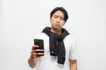 Sad and Pensive Young Asian Man Holding Smartphone with a Pouting Expression