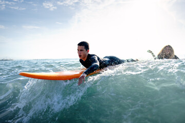 Fit couple surfing at sunset. Surfers friends having fun inside ocean. Sport and vacation concept