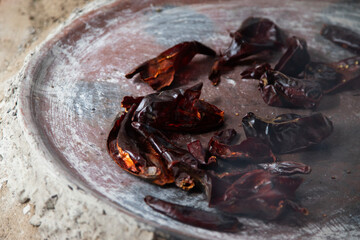 Preparing Mexican Mole Negro. Oaxaca chiles have to be cleaned, toasted on a comal over a flame and soaked in water before grinding with metate.