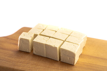 Pieces of raw tofu on a wooden board with soy beans.Vegan food ingredient in Asian cuisine, Plant based diet. food concept.