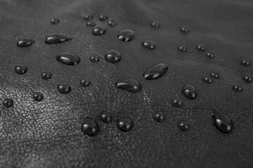 Round water drops on black green leather texture, side view, soft focus macro pattern