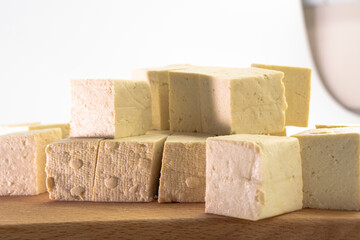 Pieces of raw tofu on a wooden board with soy beans.Vegan food ingredient in Asian cuisine, Plant based diet. food concept.