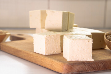 Pieces of raw tofu on a wooden board with soy beans.Vegan food ingredient in Asian cuisine, Plant based diet. food concept.