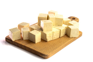 Obraz premium Pieces of raw tofu on a wooden board with soy beans.Vegan food ingredient in Asian cuisine, Plant based diet. food concept.