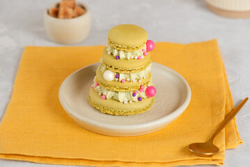 Macarons in the shape of a Christmas tree decorated with candies on a table.